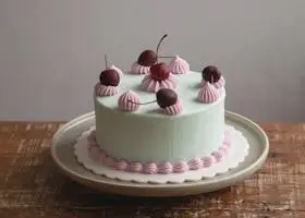A beautifully decorated layer cake with cherries and pastel frosting, perfect for dessert.